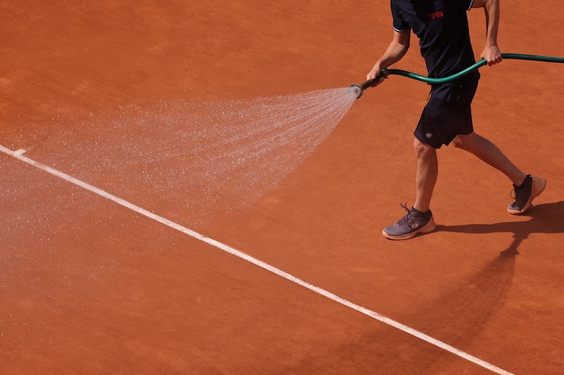 An employee sprays water on the distinctive clay of Court Philippe-Chatrier in Paris during the French Open. Photograph: Thomas Samson/AFP via Getty Images