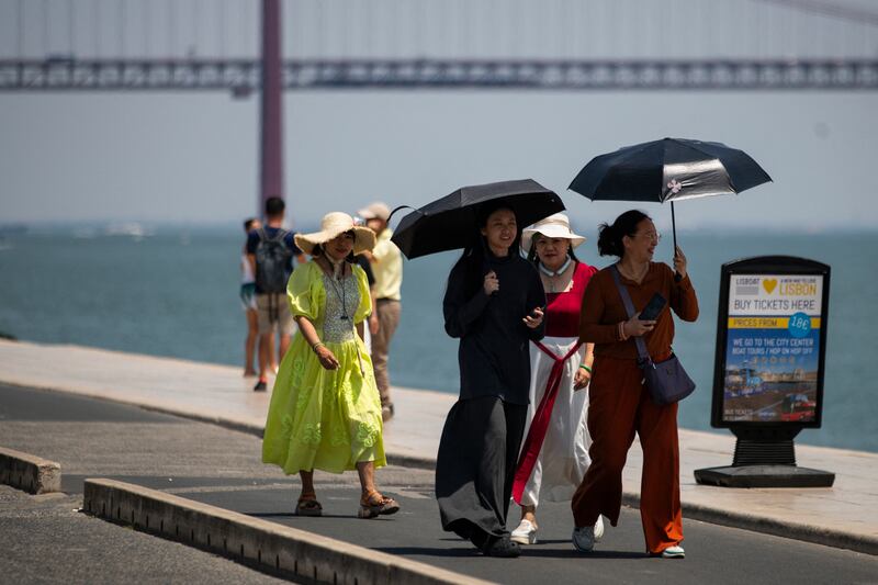 A group of women wear hats and hold umbrellas to shield themselves from the scorching sun during the first heatwave of the year in Lisbon, Portugal. Photograph: Carlos Costa/AFP/Getty