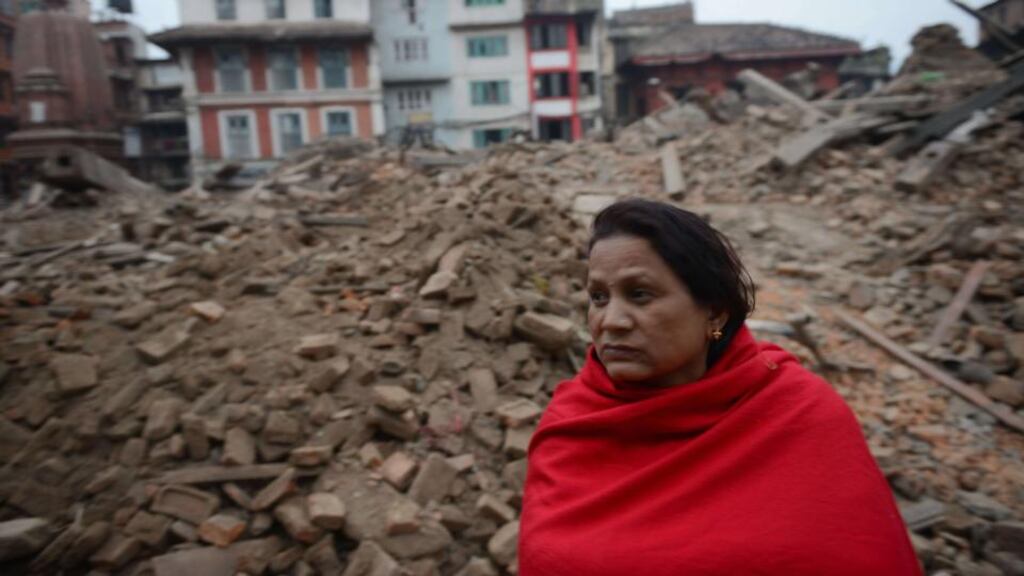 A Nepalese resident sits near buildings in Kathmandu that were  severely damaged by the earthquake which occurred on Saturday morning. Photograph: Prakash Mathema/AFP/Getty Images.