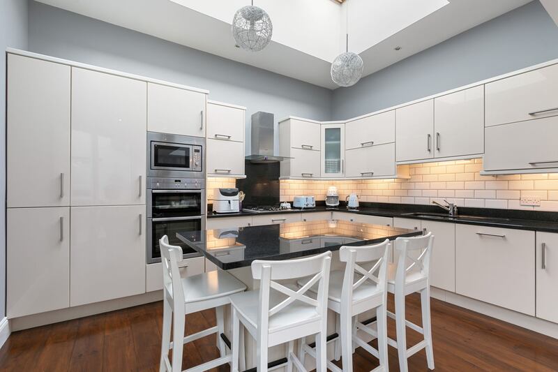The kitchen has shiny cream units and plenty of light.