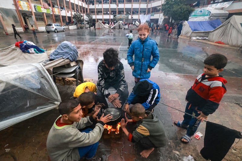 Palestinian children warm themselves around a fire at their makeshift camp in a schoolyard in Rafah, southern Gaza Strip, on December 13th, 2023, as battles continue between Israel and Palestinian militant group Hamas. Photograph: Mohammed Abed/AFP/Getty