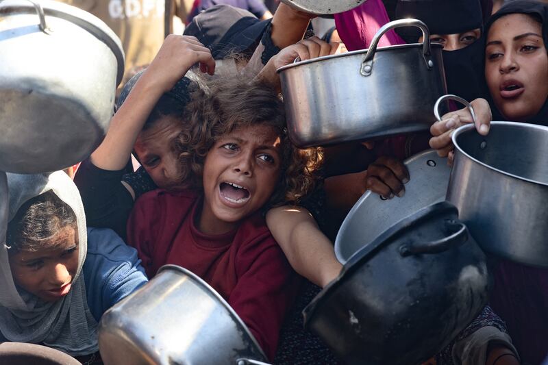 Palestinian women and children hold out their empty pots in front of a charity kitchen in Khan Younis in the southern Gaza Strip on Thursday. Photograph: AFP via Getty Images         