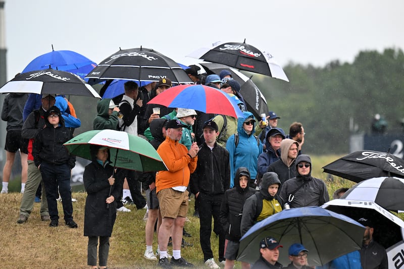 Spectators shelter from the rain under umbrellas on the opening day. Photograph: Andy Buchanan/Getty