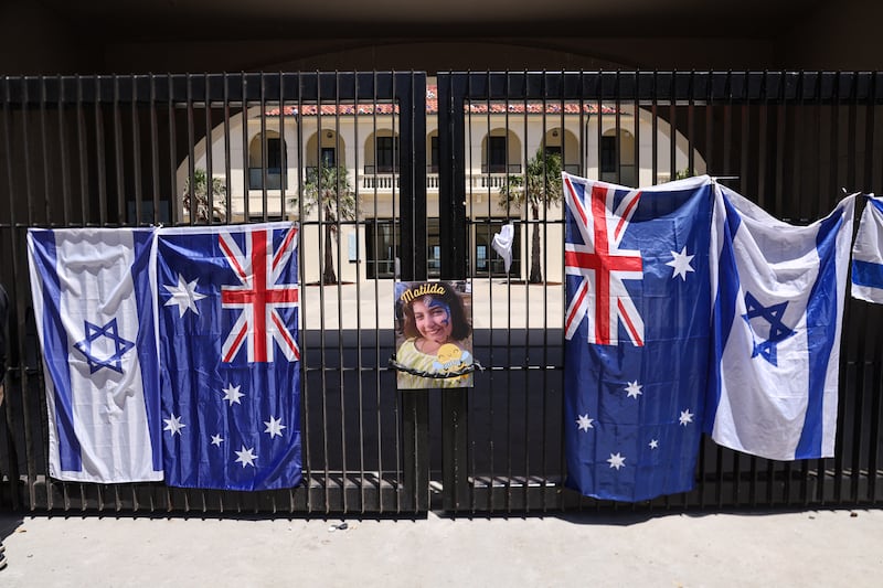 A poster of 10-year-old Matilda, who was killed in the December 14 Bondi Beach shooting attack, is hung next to flags of Australia and Israel on the gate of the Bondi Pavilion, in Sydney on December 18, 2025. The attack at Bondi Beach on December 14 was one of the deadliest in Australian history. (Photo by DAVID GRAY / AFP via Getty Images)