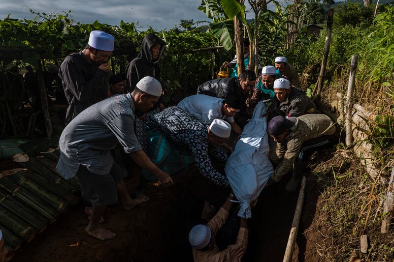 Community members bury the body of Eis (70), who died from illness in a temporary shelter after their house was damaged by the earthquake. Photograph: Ulet Ifansasti /New York Times)