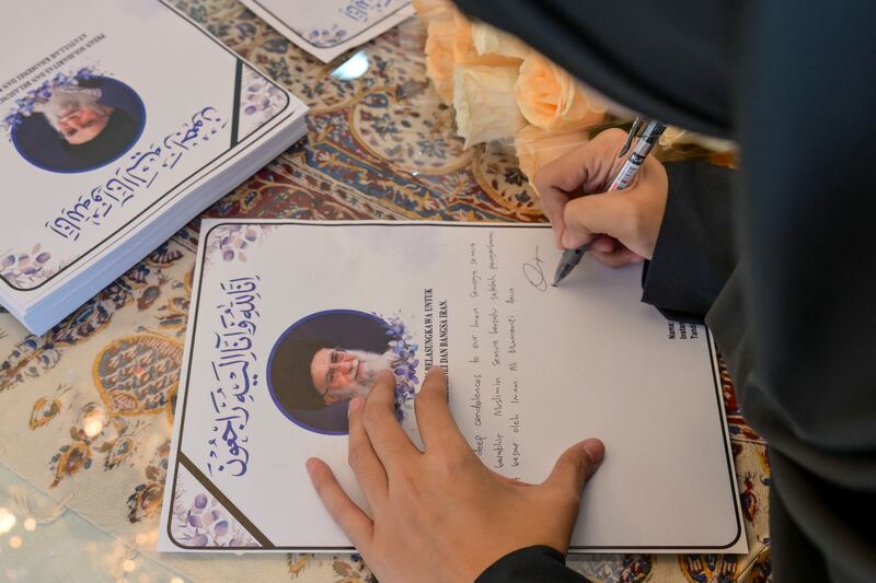 A mourner writes a message of condolences following the death of Iranian supreme leader Ayatollah Ali Khamenei. Photograph: BAY ISMOYO / AFP via Getty Images