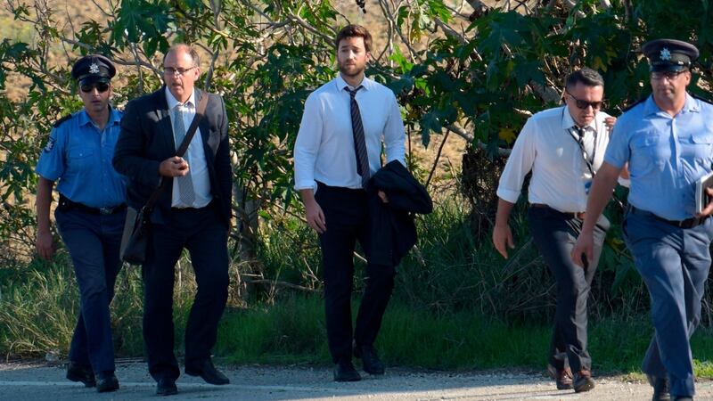 Matthew Caruana Galizia (centre) and Peter Caruana Galizia (second left), son and husband of journalist Daphne Caruana Galizia, walk past the wreckage of a car bomb that killed her in Bidnija, Malta. Photograph: AFP/Getty Images