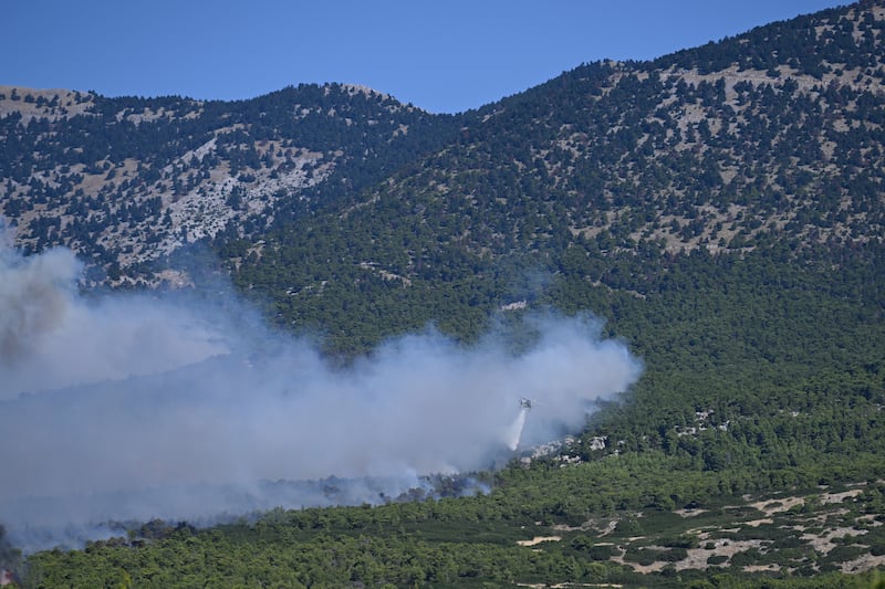 A helicopter drops water over a smoke-filled forest during a wildfire near Porto Germeno, northwest of Athens, Greece. Photograph: Michael Varaklas/AP