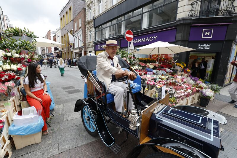 Jim Kiernan in his 122-year-old motor car and flower trader Olivia Cleary near Davy Byrne's pub on Dublin's Duke Street on Tuesday. Photograph: Nick Bradshaw/ The Irish Times
