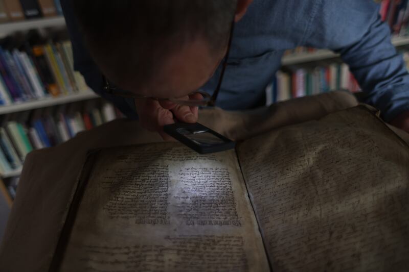 Dr John Gillis carefully examines a page of the original manuscript, The Red Book of Ossory