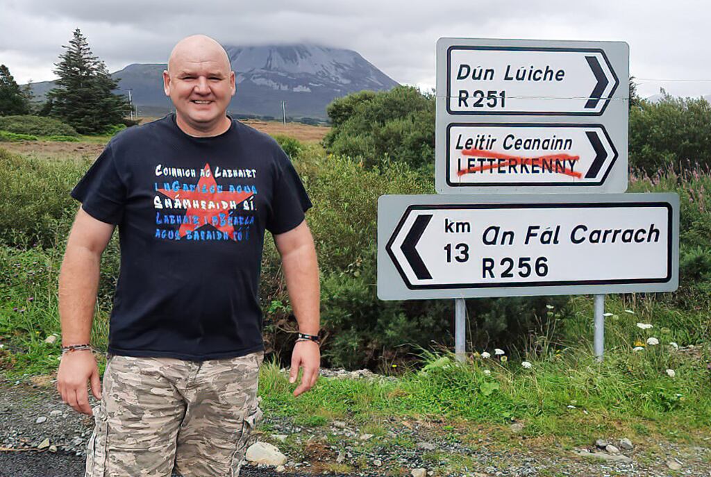 Cllr Micheál Cholm Mac Giolla Easbuig at one of the paint-sprayed signs in Donegal: `We have vandalism on all sorts of signs around the county and nobody condemns it. But yet when somebody takes a stance on the Irish language, we treat it as vandalism.' Photograph: Joe Boland