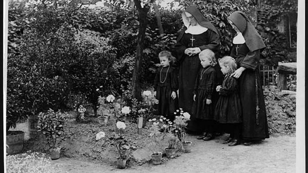 Two nuns and three young girls at the grave of Maj William Redmond in Locre, Belgium, during the first World War. Redmond was mortally wounded during the Battle of Messines. Photograph:: John Warwick Brooke/National Library of Scotland