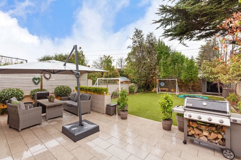 There’s a good-sized patio in the back garden next to an artificial grass lawn bordered by mature shrubs and trees