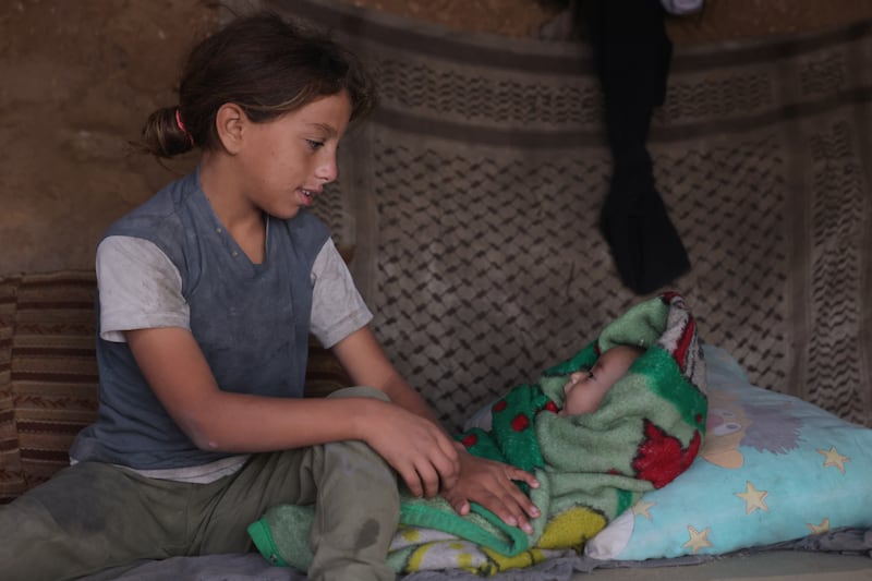 Hala (11) a displaced Palestinian girl from the Naqla family in Jabalia in the northern Gaza Strip watches over her two-month-old brother Hassan inside their family's temporary cave in Al-Zawayda on October 9 2025. Photograph: Bashar Taleb/ AFP           