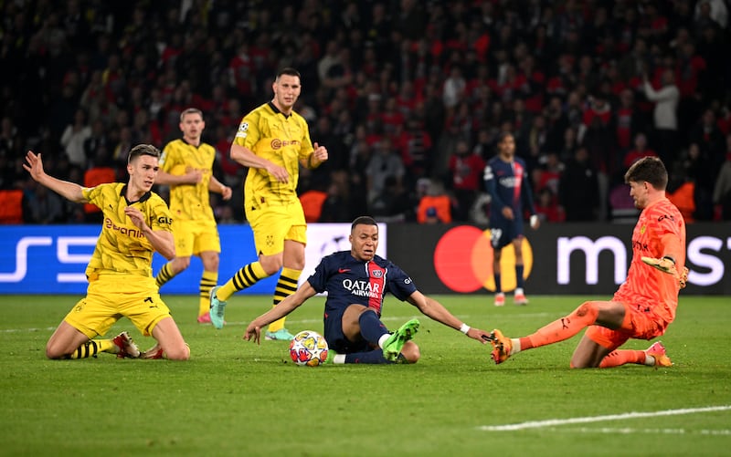Kylian Mbappé of Paris Saint-Germain goes down as he attempts a shot while under pressure from Gregor Kobel of Borussia Dortmund. Photograph: Matthias Hangst/Getty Images
