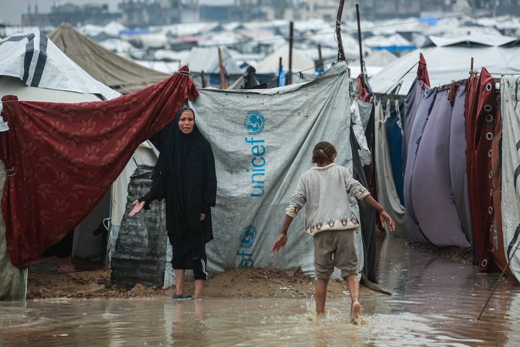 People wade through water at a makeshift camp housing displaced Palestinians in Deir al-Balah, in the central Gaza Strip. Photograph: Bashar Taleb/ AFP via Getty Images