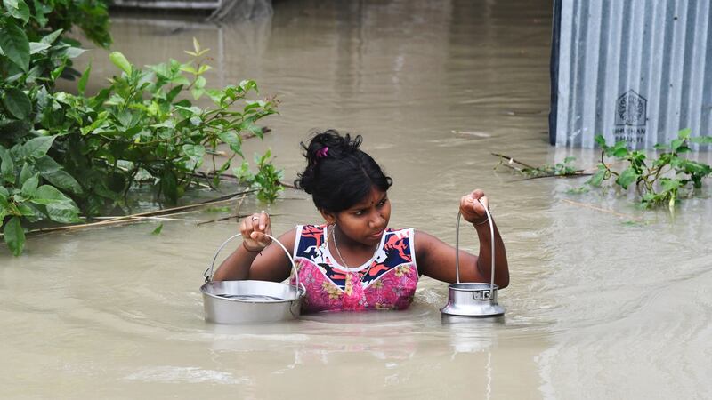 An Indian girl carries drinking water as she wades through flood waters at Pabhokathi village in Morigaon district of India’s Assam state. Photograph: Biju Boro/AFP via Getty Images)