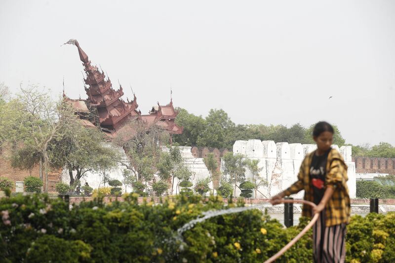 A woman pours water on plants in front of the damaged Mandalay palace. Photograph: Nyein Chan Naing/EPA