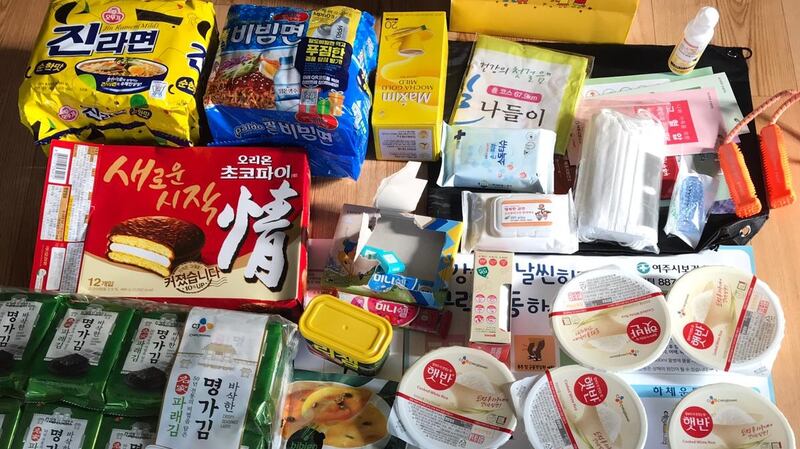 A selection of foods supplied by a local council in South Korea to each new arrival for the 14-day self-quarantine. It includes masks, a thermometer and chocolates. Photograph: Yongnam Park