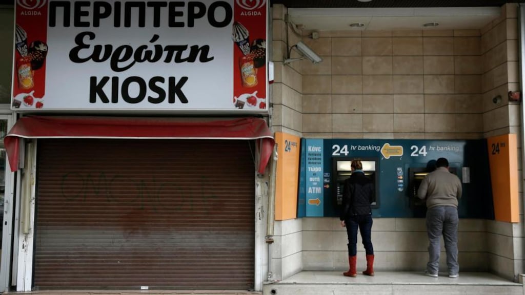 Bank customers make transactions at an automated teller machine (ATM) outside a closed branch of the Bank of Cyprus in Nicosia. Photograph: Yorgos Karahalis/Reuters