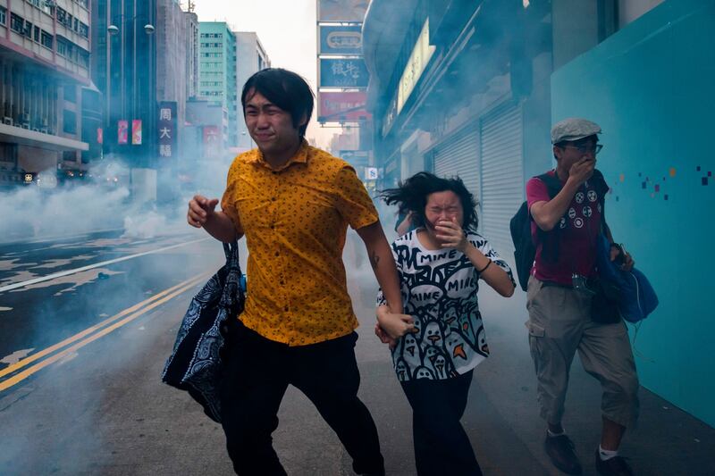 Protesters and bystanders along Nathan Road react from tear gas fired by police during the pro-democracy march in the Kowloon district. Photograph: Ed Jones/AFP/Getty