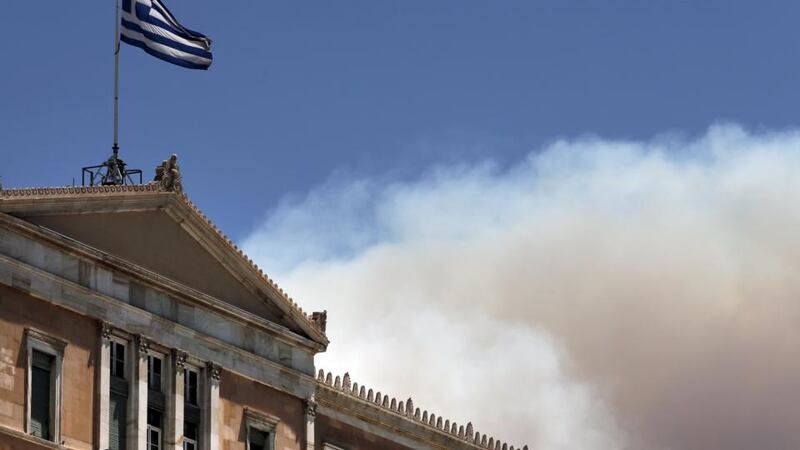 A Greek national flag flutters atop the parliament building as smoke from  wildfire rises in Athens, Greece, July 17th, 2015. Photograph: Alkis Konstantinidis/Reuters