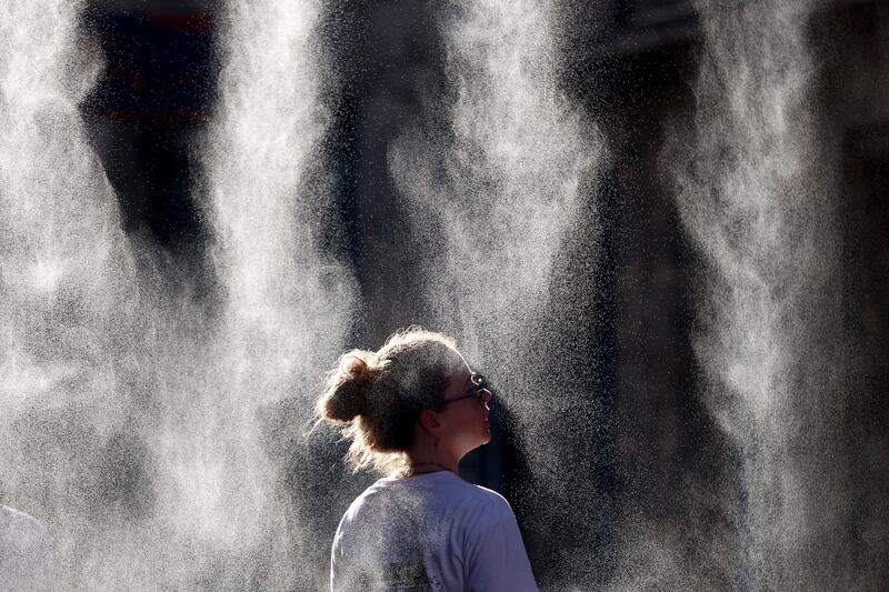 A woman cools off under a mist sprayer during the annual street music festival 'Fete de la Musique' during a heatwave in Bordeaux. Photograph: ROMAIN PERROCHEAU / AFP via Getty Images