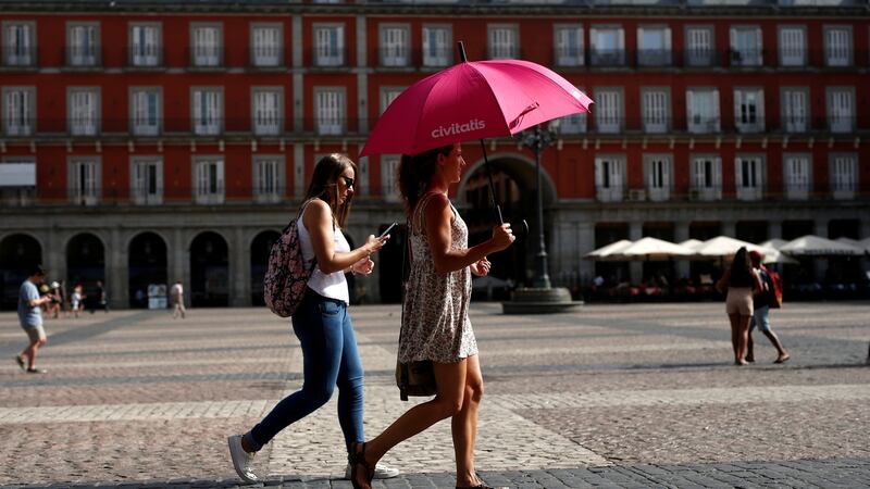 A woman protects herself with an umbrella as she walks at Plaza Mayor, as temperatures soar across Europe, in Madrid Spain. Photograph: Javier Barbancho/Reuters