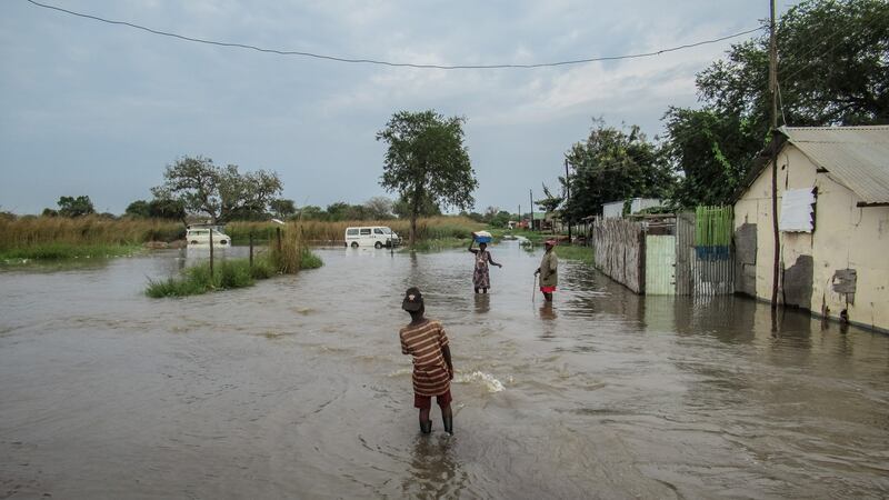 A woman carries some belongings from her flooded home in Elegu, northern Uganda, on the border with South Sudan. Photograph: Sally Hayden