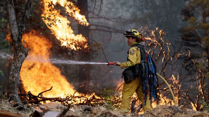 A firefighter hoses down flames as a wildfire advances onto a residential district in Redding, California. Photograph: Marcio Jose Sanchez/AP.