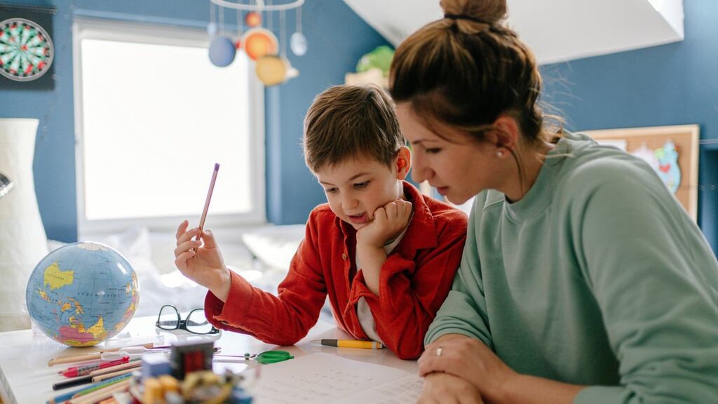 Photo of a young boy being homeschooled by his mother in his bedroom