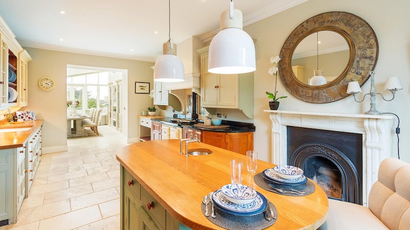 The kitchen is smart, with a timber-topped island unit, marble fireplace, cream Aga and cream kitchen units.