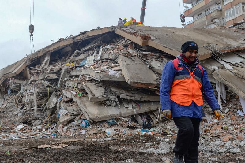 A man walks past a collapsed building as rescuers search for victims and survivors in Diyarbakir, Turkey. Photograph: Ilyas Akengin/AFP via Getty Images