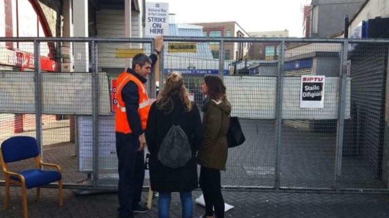 A striking worker speaks with tourists at a locked-up Tara Street Dart station in Dublin during the rail strike. Photograph: Frank Miller/The Irish Times