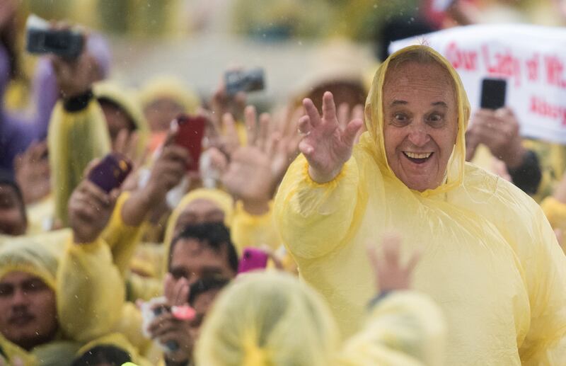 2015. Pope Francis (R) wears a plastic poncho as he waves to well wishers after a mass in Tacloban on January 17, 2015. Photograph: Johannes Eisela / AFP