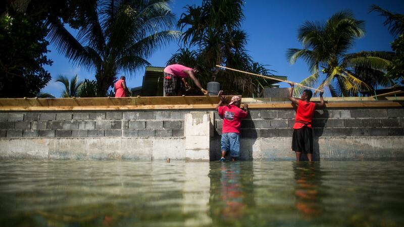 A group of men rebuild a sea wall on Ejit, Marshall Islands, one of a number of Pacific islands threatened by rising sea levels. (Photograph: Josh Haner/The New York Times)