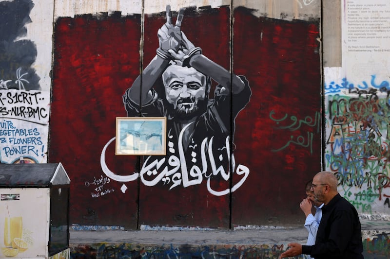 Men walk past a section of Israel's separation barrier painted with a portrait of Palestinian leader Marwan Barghouti, held in an Israel jail, on November 6th, 2023 in Bethlehem in the occupied West Bank. Photograph: Hazem Bader/AFP 