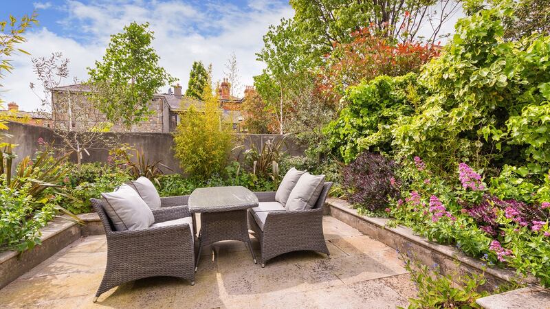 The  northwest-facing elevated 9-metre-long rear garden has a raised seating area and Astroturf patch