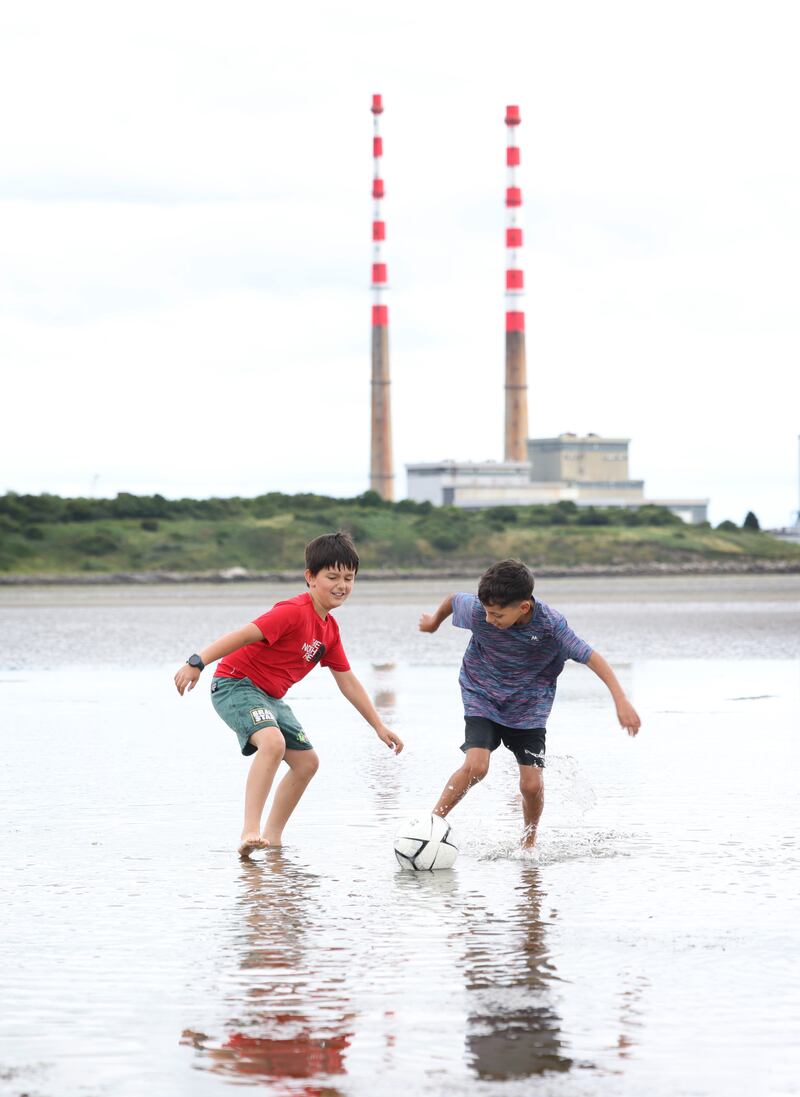 Best friends Denis Zele (11) in red and Karim Eldali (10) from Dublin 8 cool off with a kick around in the sea at Sandymount, Dublin on Monday.  Photograph: Bryan O’Brien
