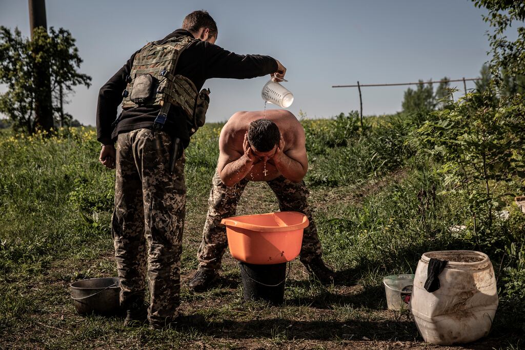 Samara, 48, the deputy leader of a Ukrainian military unit, washes up over a tub during a lull in fighting on the front line in the Donetsk region near Izyum, Ukraine, on May 27th. Photograph: Finbarr O’Reilly/New York Times