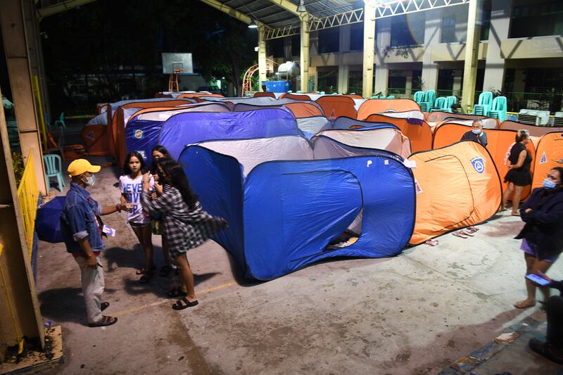 People stand next to tents at an evacuation centre in Quezon city as Super Typhoon Noru hit the Philippines. Photograph: Ted Aljibe/Getty Images
