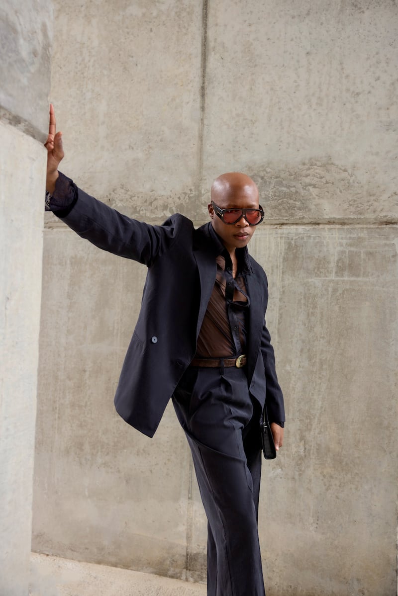 Kwanele Nomoyi at a friend's birthday celebration, wearing a sheer St Laurent shirt with an Icicle suit styled with a crocodile-effect Coach bag, Eleventy belt and red-lens Tom Ford sunglasses. "The look balances tailoring with a slightly more directional silhouette"