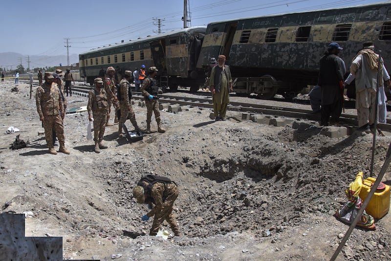 Army officials examine a crater and damaged train coaches at the site of the bomb explosion. Photograph: Arshad Butt/AP