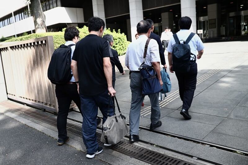 A 38-year-old Japanese man, who has remained anonymous, walks with his legal team as they enter a Tokyo court this week to attend a first hearing after suing his employer who allegedly penalised him for taking paternity leave. Photograph: Behrouz MEHRI/AFP/Getty Images