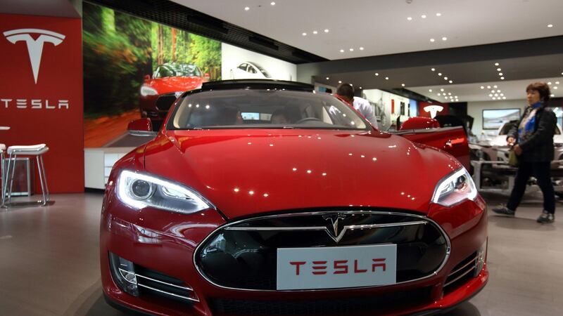 Customers look at a Tesla Motors Inc. Model S electric vehicle  in Beijing, China. The company expects a a surge in orders for its  plug-in electric car. Photographer: Tomohiro Ohsumi/Bloomberg
