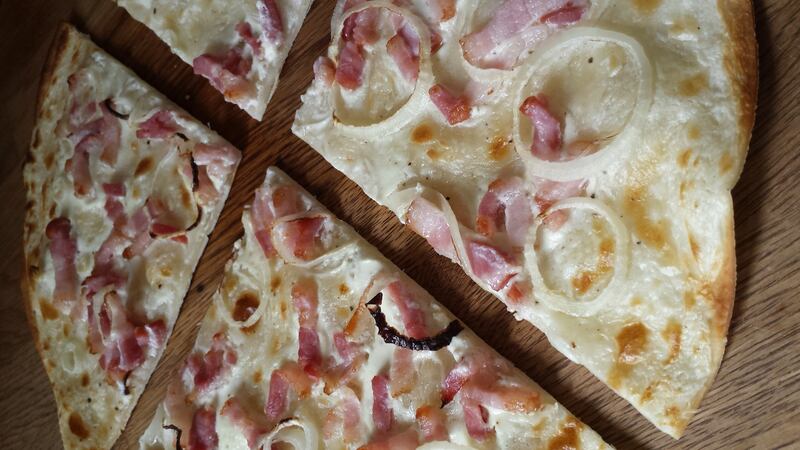 Flammkuchen has   a very thin base somewhere between pizza dough and fresh pasta, topped traditionally with seasoned crème fraîche, bacon and onions.