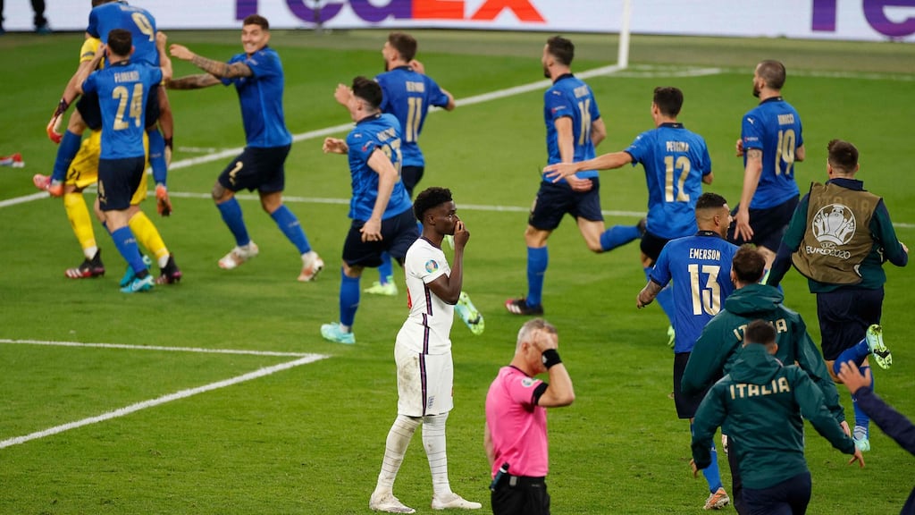 England’s Bukayo Saka reacts after missing a penalty as Italy’s players celebrate winning Europ 2020. Photo: John Sibley/AFP via Getty Images