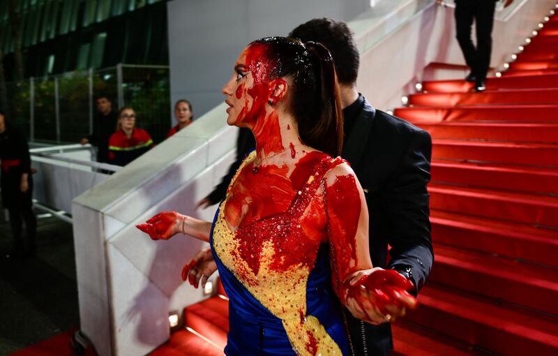 A woman wearing a dress in the blue and yellow of Ukraine covered herself in fake blood at the premiere of the allegorical horror film Acide. Photograph: Christophe Simon/AFP via Getty