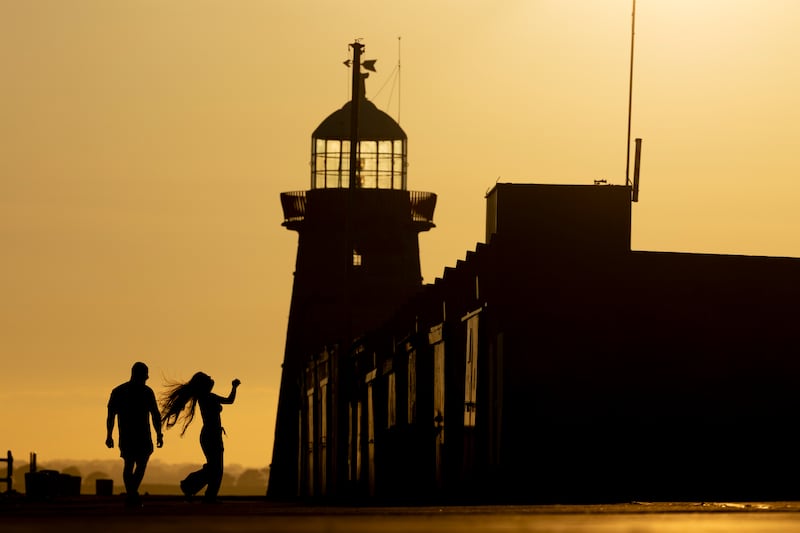 A couple on the East Pier in Howth  with the Howth Lighthouse in background at sunset on Sunday. Photograph: Tom Honan