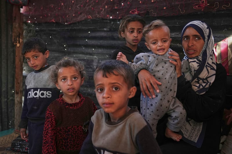Wedad Abdelaal, right, and her nine-month-old son Khaled who suffers from malnutrition and her children Ahmed (7) and Maria (4), both showing signs of malnutrition also, pose for a photo in their tent at a camp for displaced Palestinians. Photograph: Abdel Kareem Hana/AP